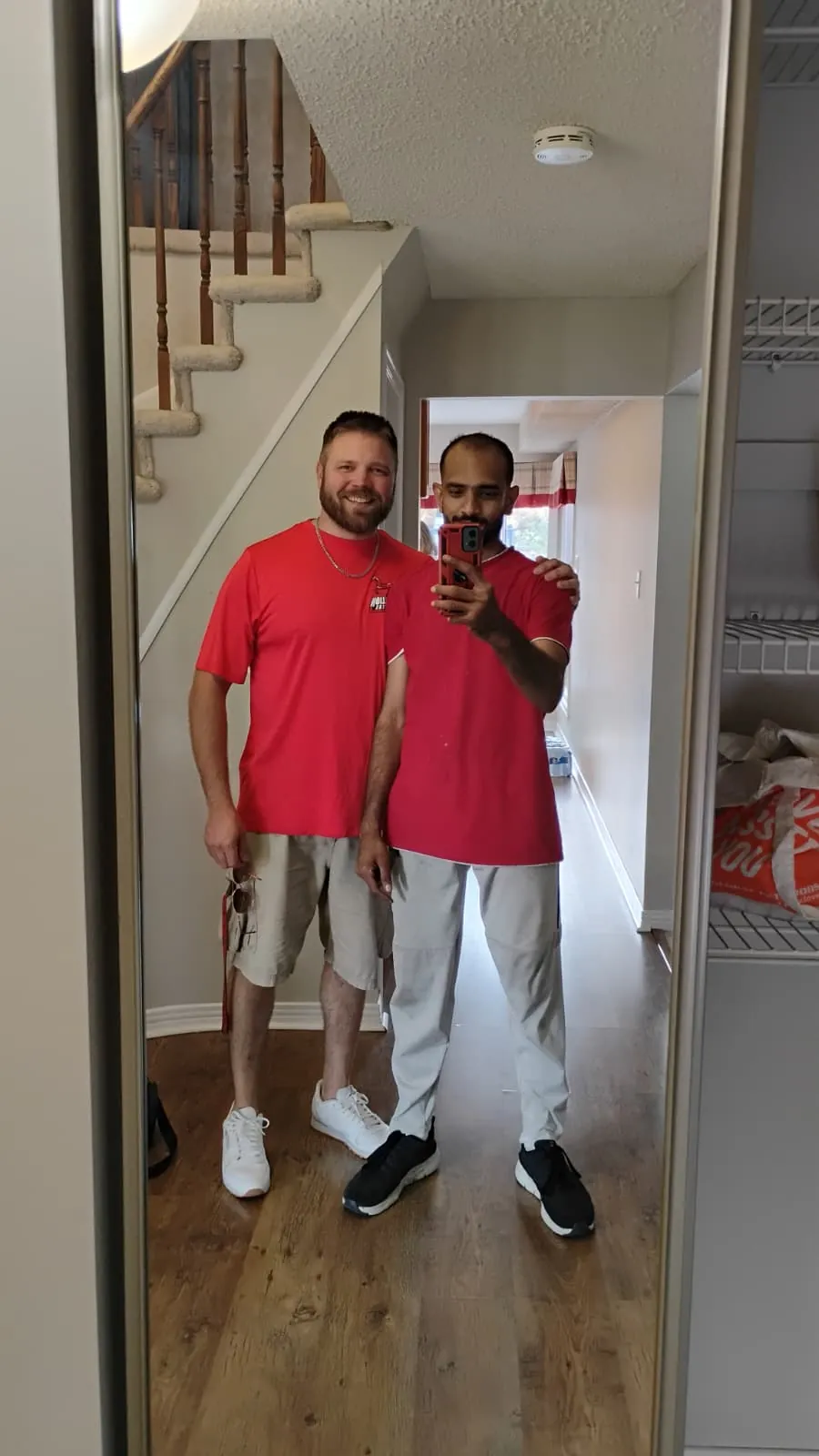 Two Stallion crew members in branded red shirts, photographed in a hallway mirror