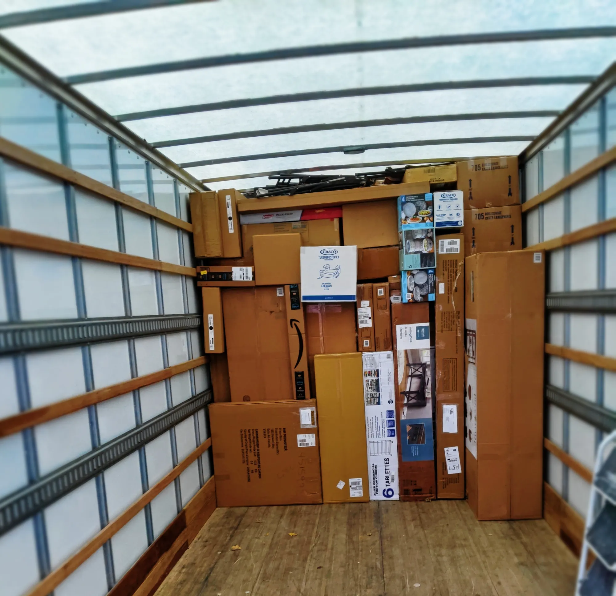 The open back of a moving truck packed floor to ceiling with cartons and flat-packed furniture
