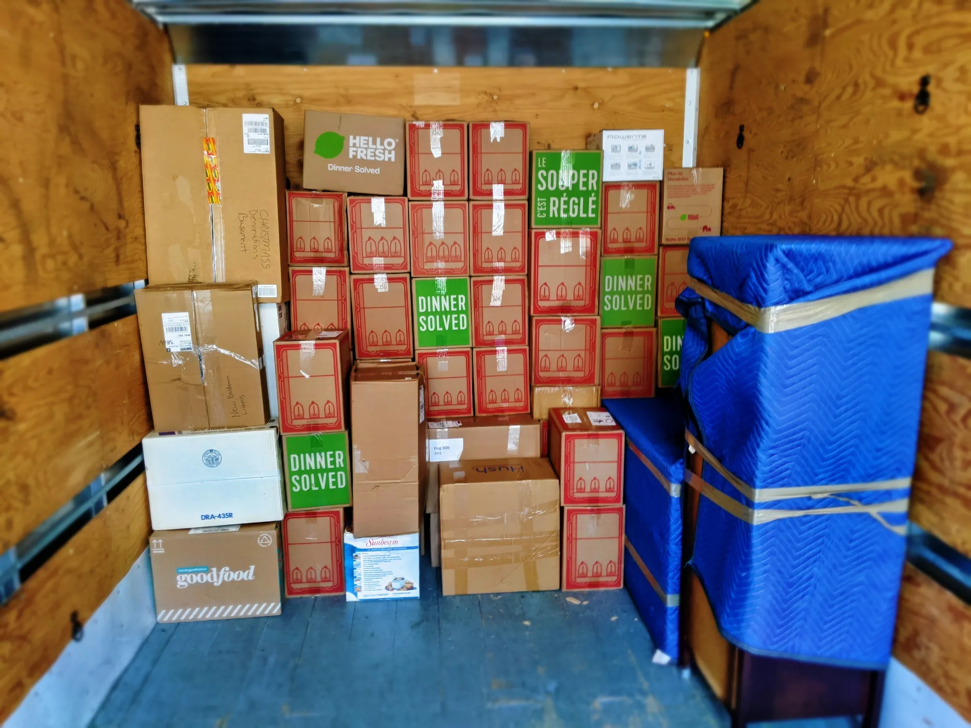 A Stallion truck loaded floor to ceiling with neatly stacked cartons beside furniture wrapped in blue moving blankets and taped