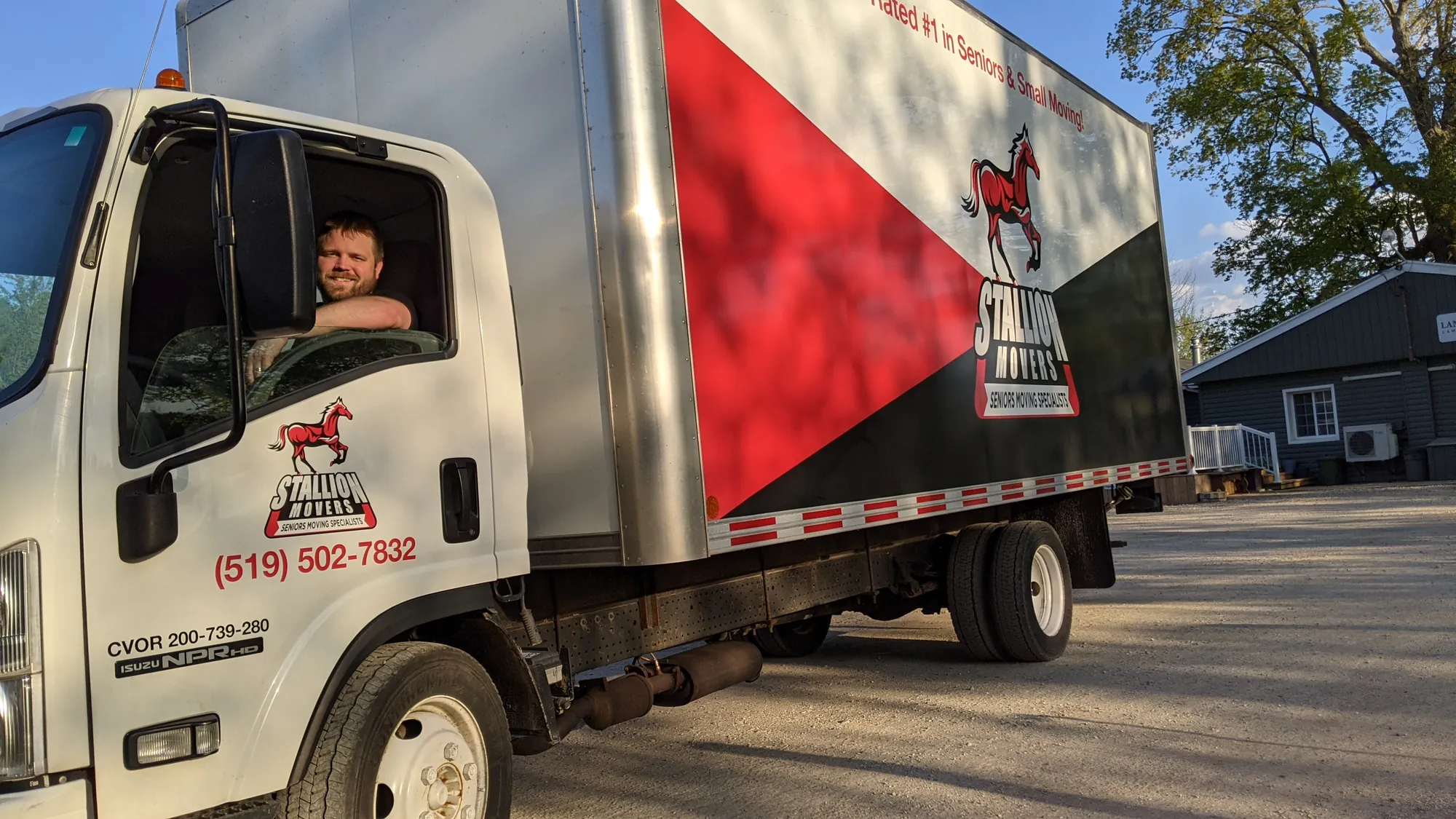 The owner of Stallion Movers leaning out of the cab of a Stallion truck in low evening sunlight