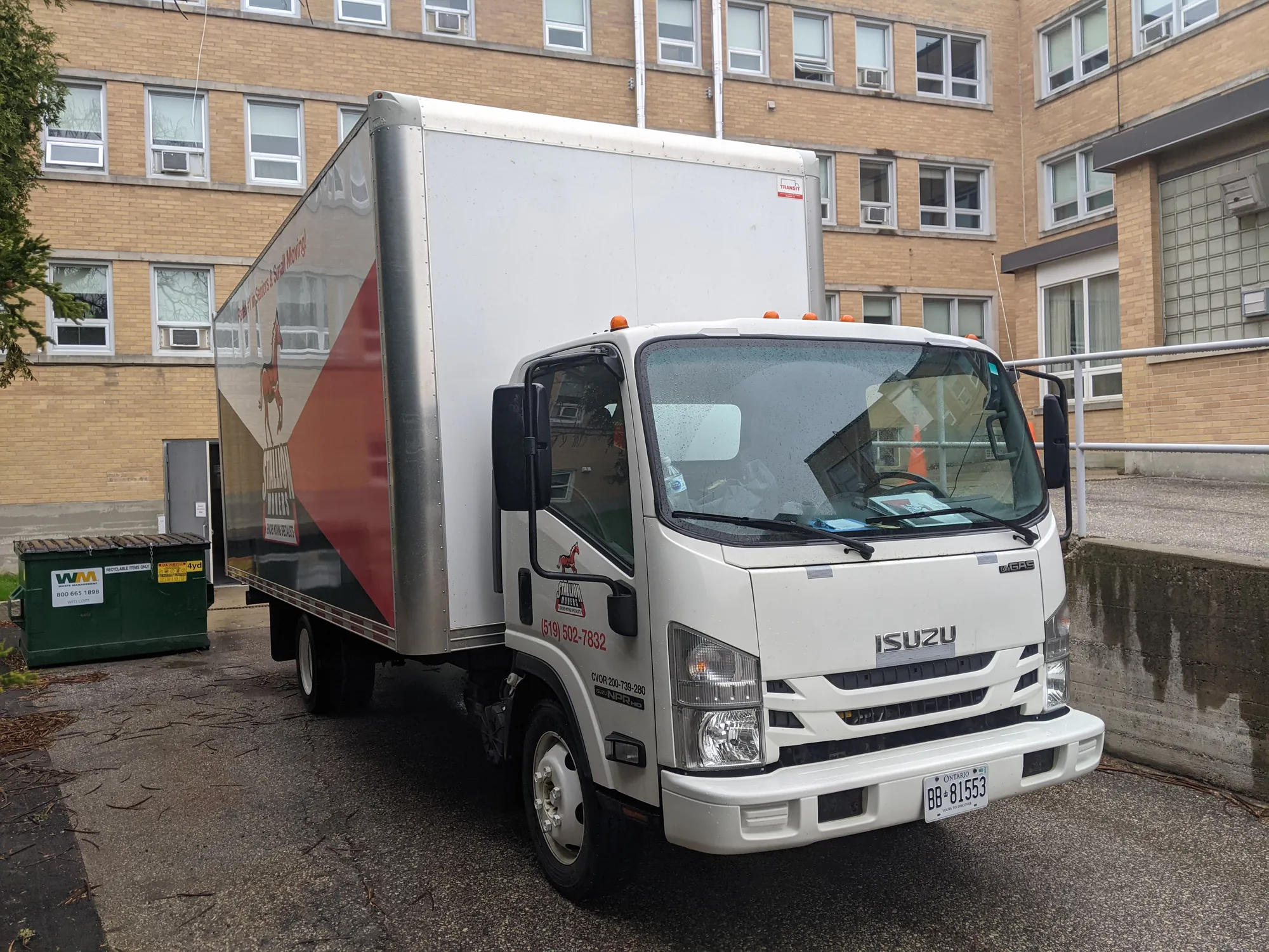 A Stallion moving truck parked outside a low brick institutional building