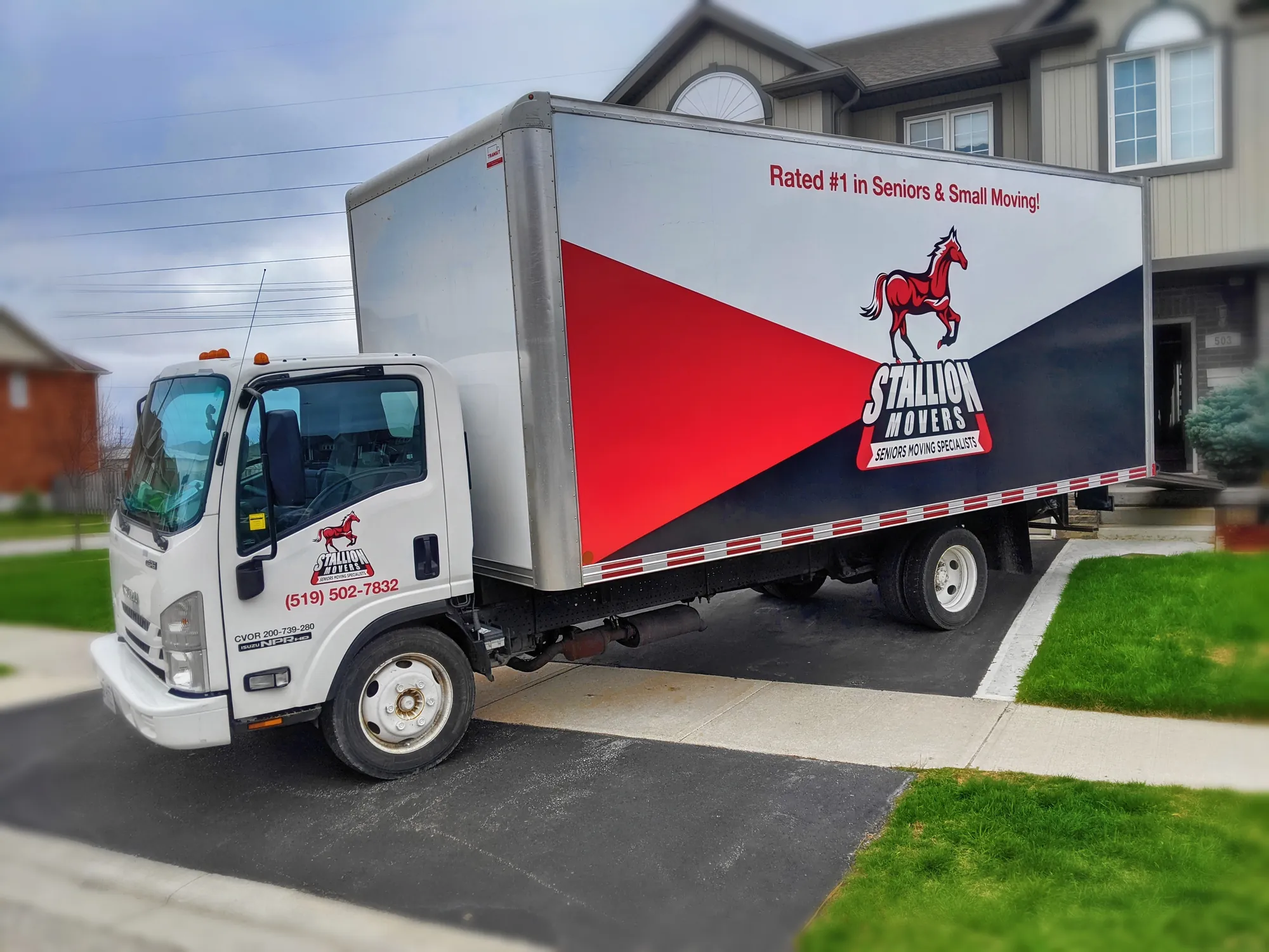 A Stallion moving truck with its rear doors open outside a suburban house