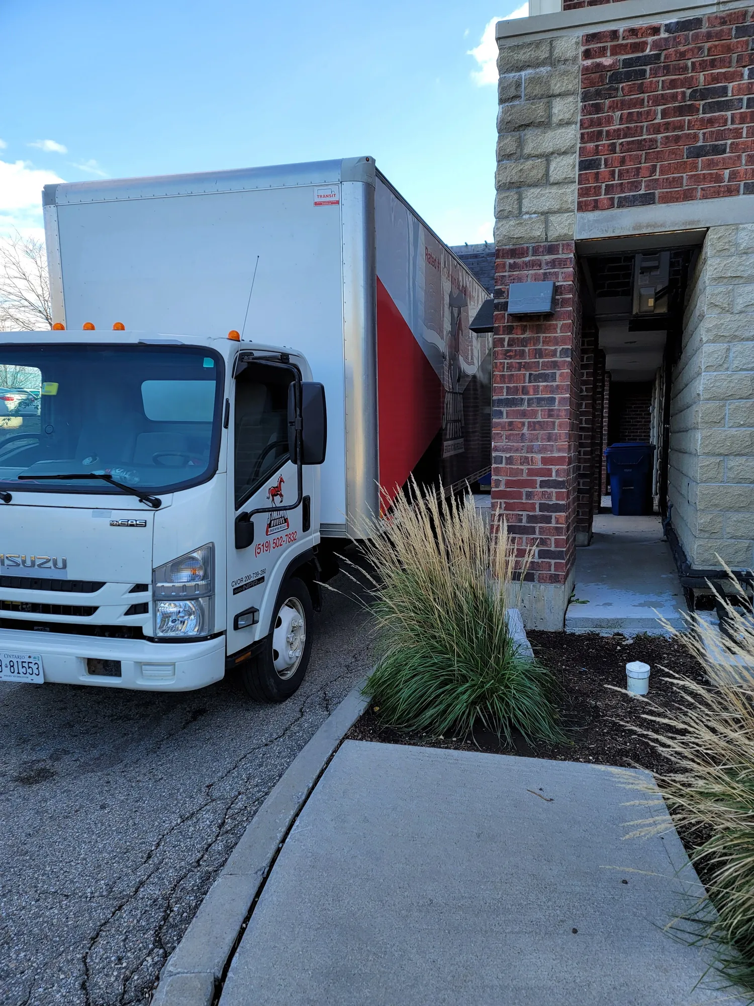 A Stallion moving truck backed into a narrow paved service entrance between two brick walls