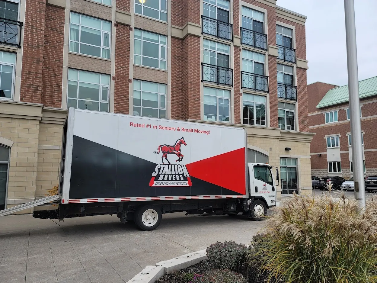 A Stallion moving truck with its loading ramp down at the main entrance of a residential tower